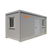 Grey portable container building with a door and two barred windows; HOMS Rentals logo on the side (used as a small office or storage unit)