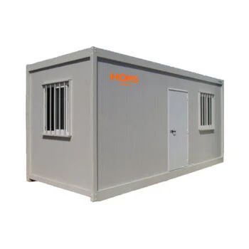 Grey portable container building with a door and two barred windows; HOMS Rentals logo on the side (used as a small office or storage unit)